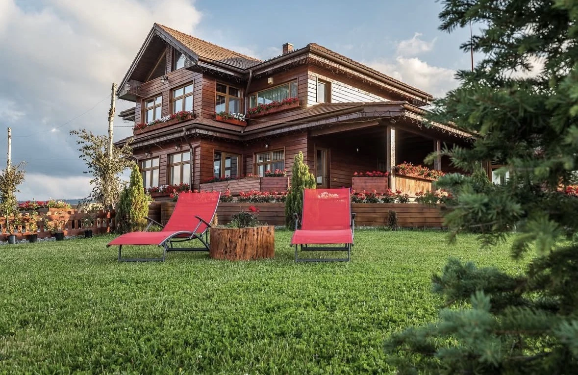 Pensiunea Turistică Vălari, clădire din lemn cu grădină și șezlonguri roșii